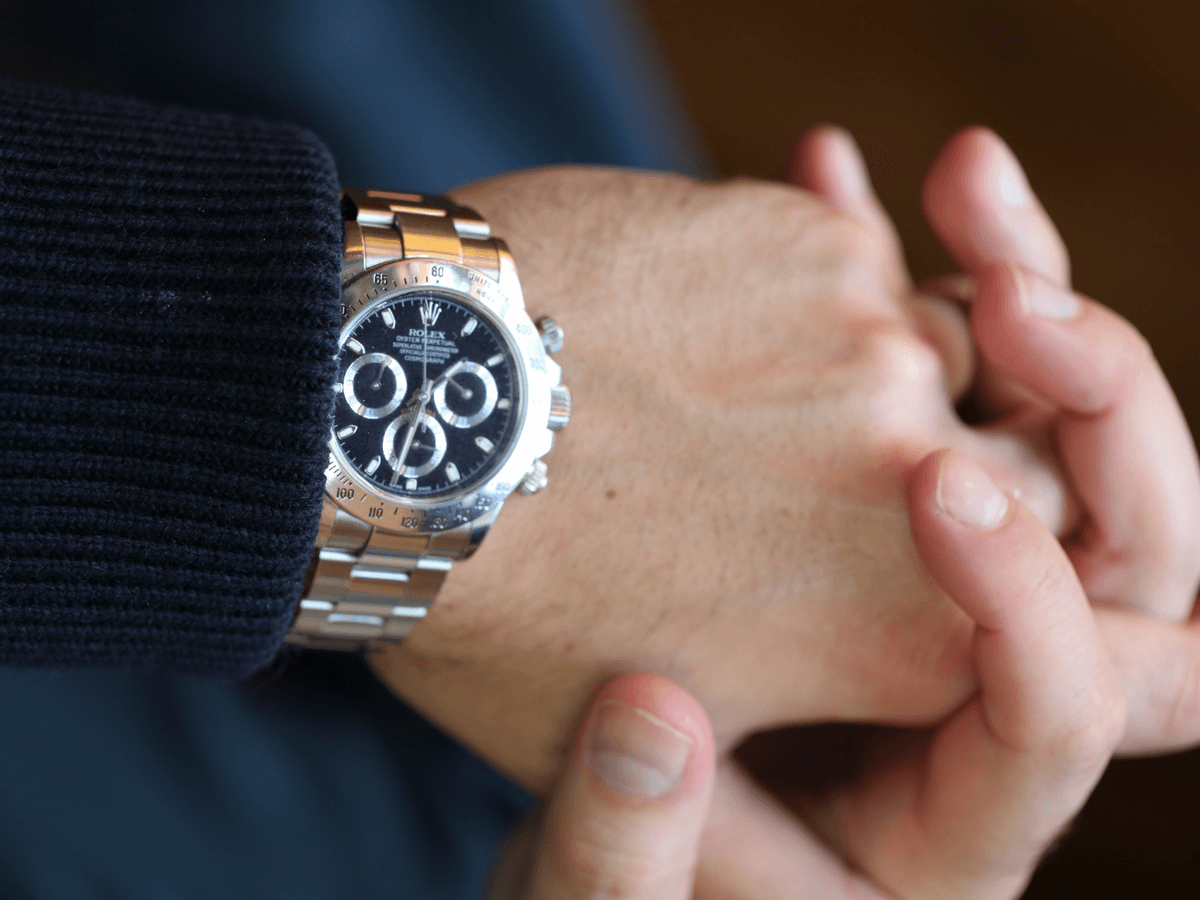 Seseorang dengan sweater biru mengenakan jam tangan stainless steel Rolex